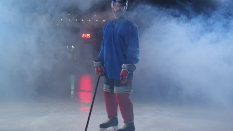 Professional-hockey-player-with-a-stick-accelerates-on-the-ice-and-stops-abruptly-in-front-of-the-camera-looking-straight-into-the-camera